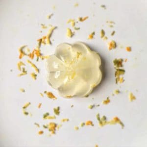 A golden yuzu marmalade jelly in the shape of a flower decorated with lemon zest