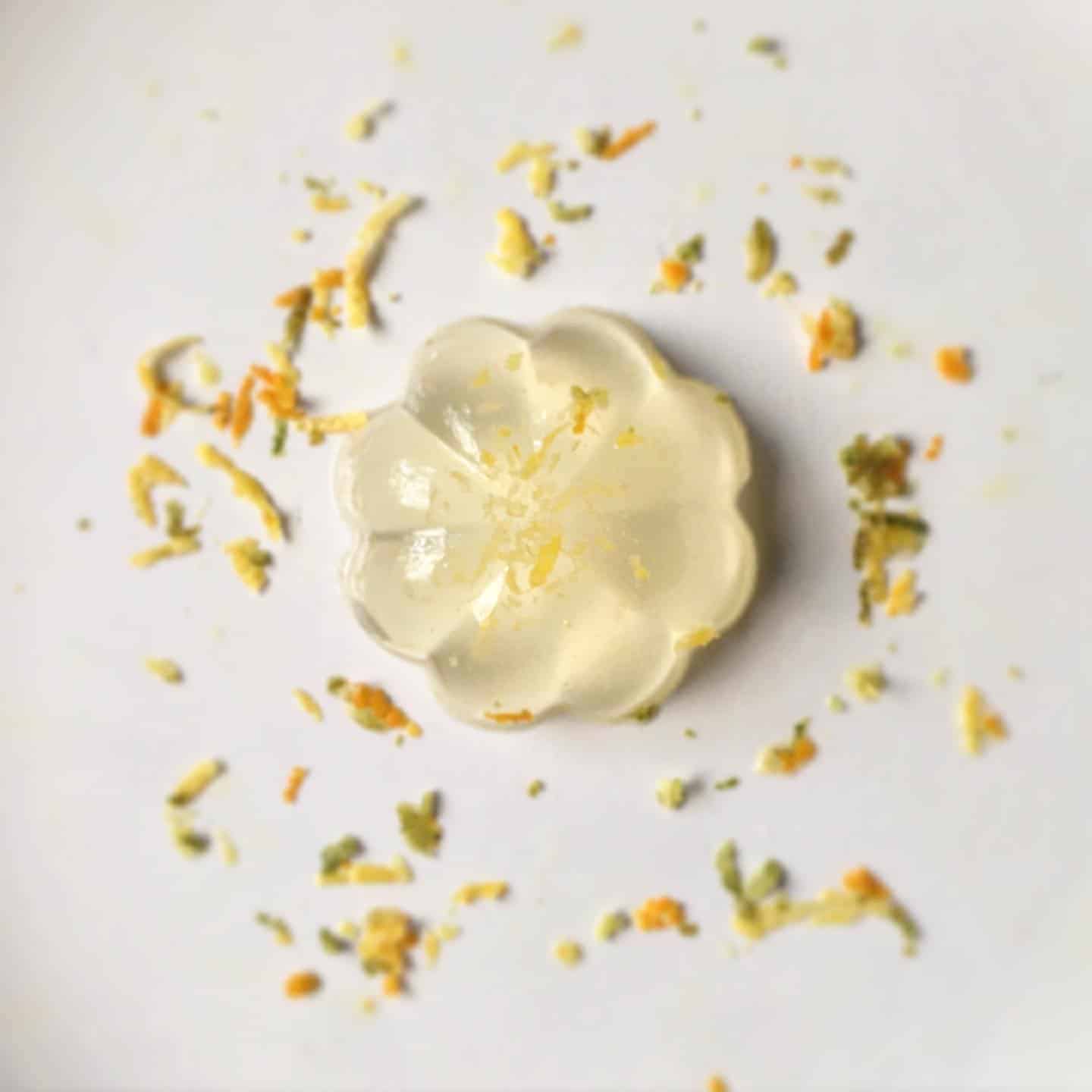 A golden yuzu marmalade jelly in the shape of a flower decorated with lemon zest