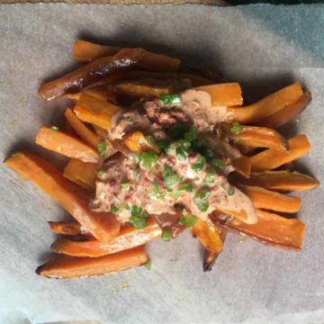 Close-up of sweet potato fries topped with spicy sambal mayo.