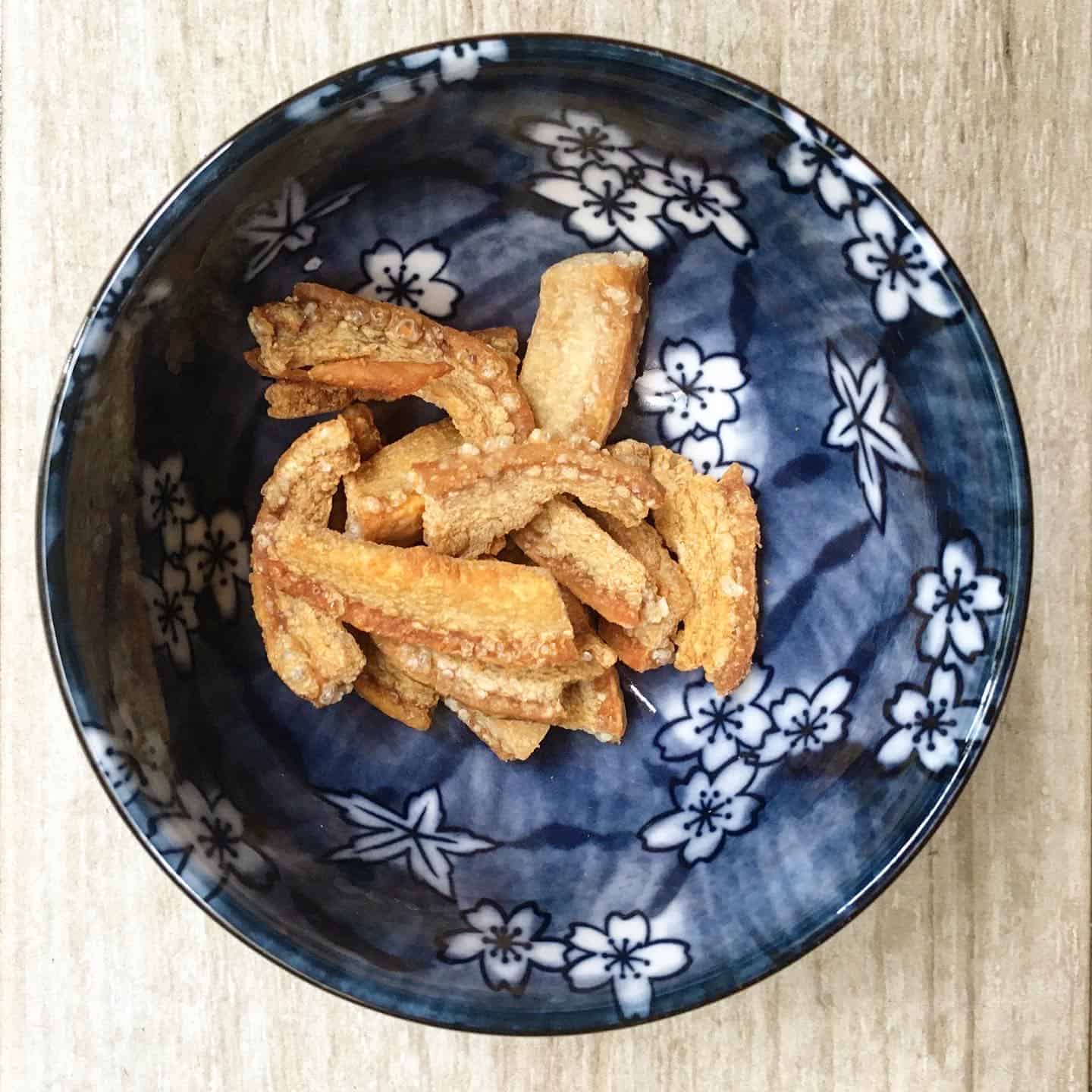 Crispy pork crackling in a blue bowl