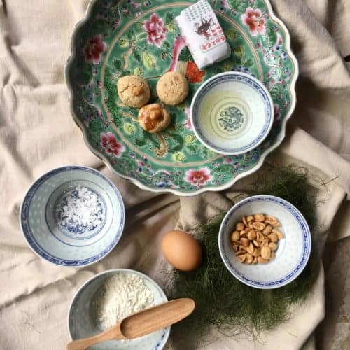 Chinese peanut cookies on a plate with its ingredients peanuts, peanut oil, flour, sugar and egg