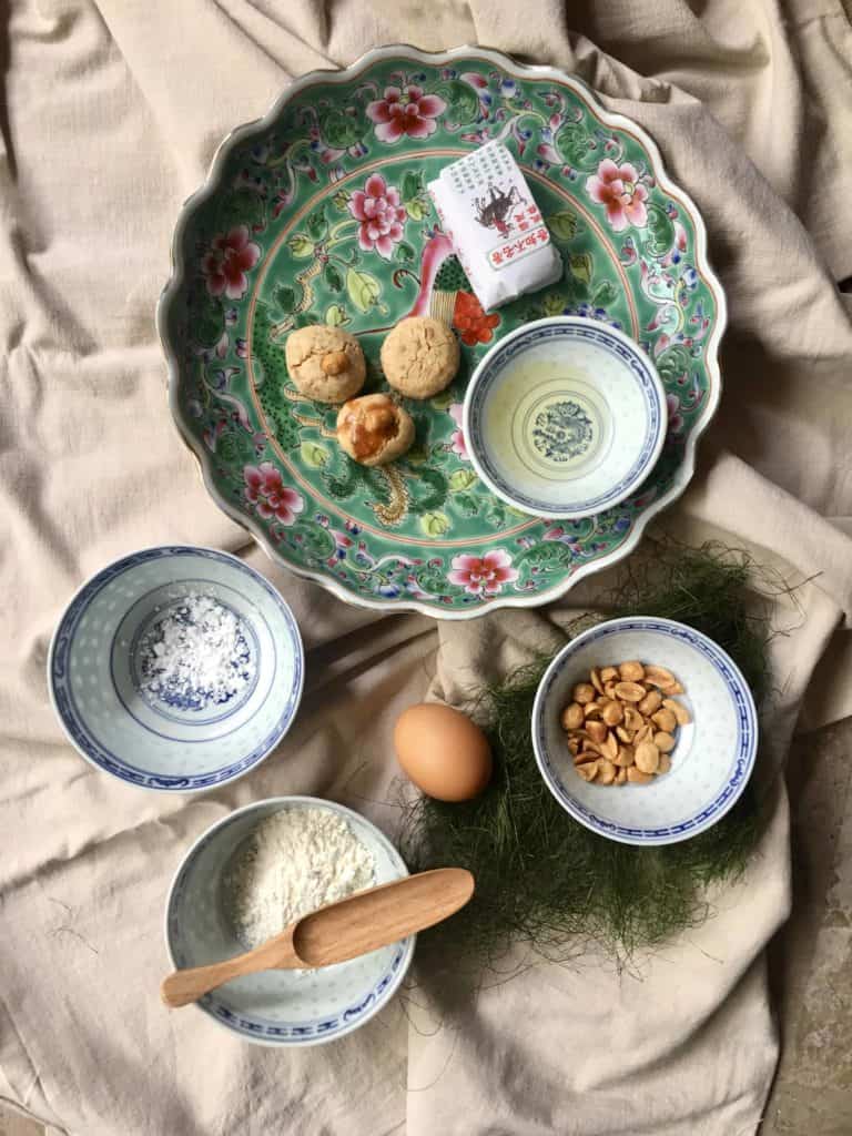 Chinese peanut cookies on a plate with its ingredients peanuts, peanut oil, flour, sugar and egg 