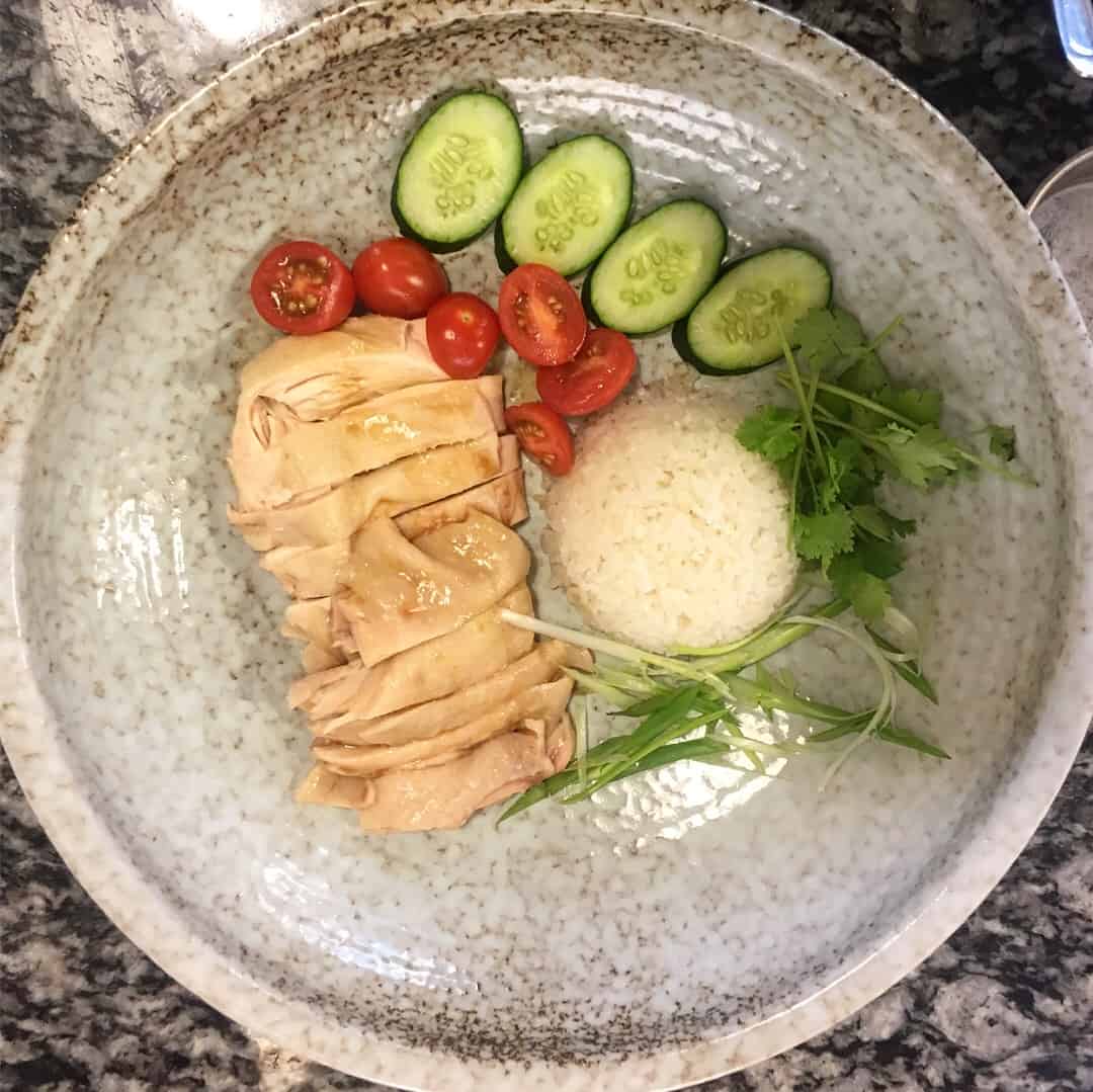 Singapore Hainanese Chicken Rice with cucumbers and tomatoes.