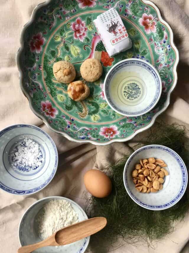 Chinese peanut cookies on a plate with its ingredients peanuts, peanut oil, flour, sugar and egg