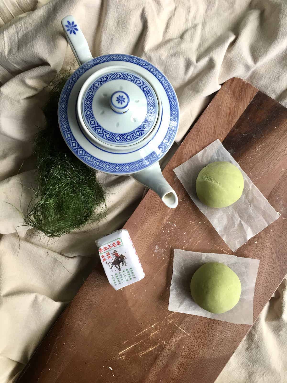 2 green matcha buns with a Chinese tea pot.