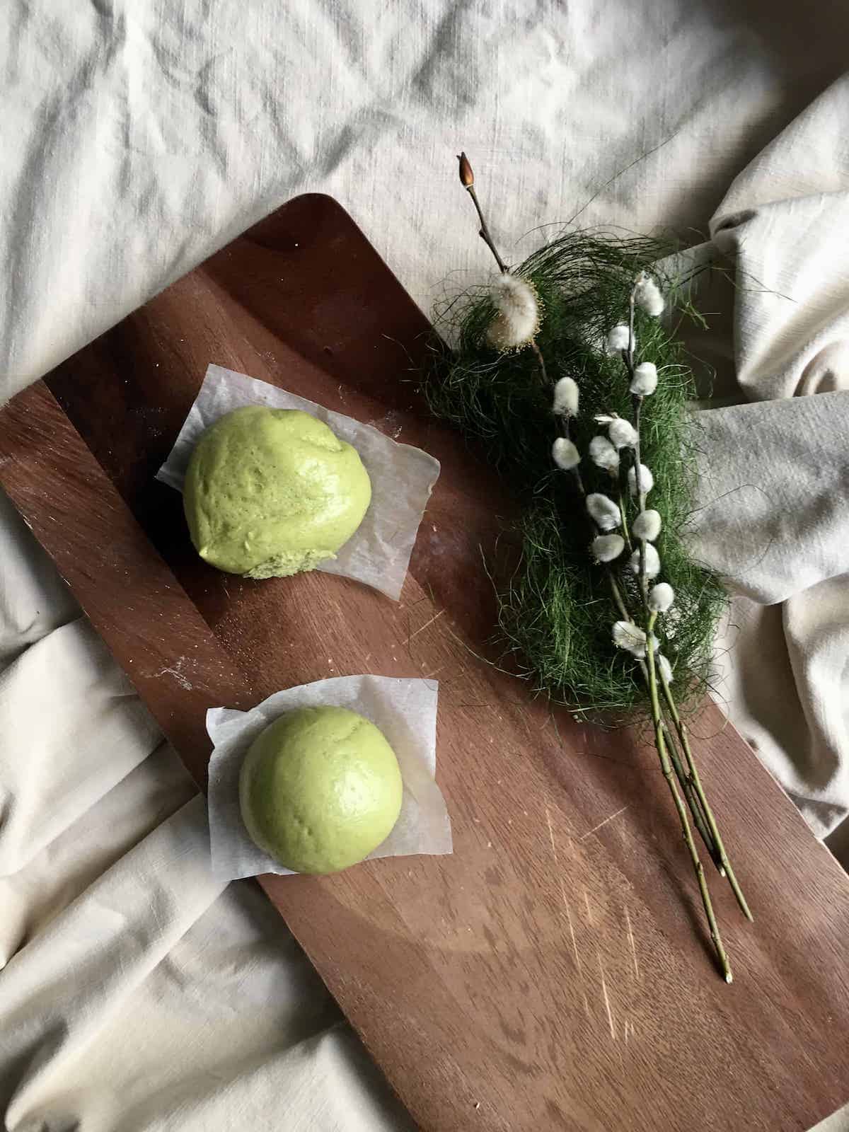 2 green matcha mantou buns, 1 wrinkled and 1 smooth, due to differing steaming methods.