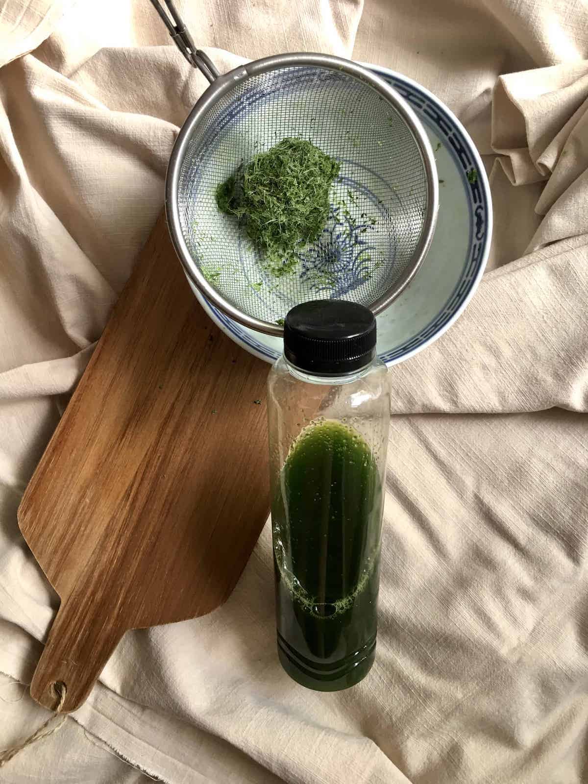 Bottle of homemade pandan juice, next to the sieved pandan pulp.