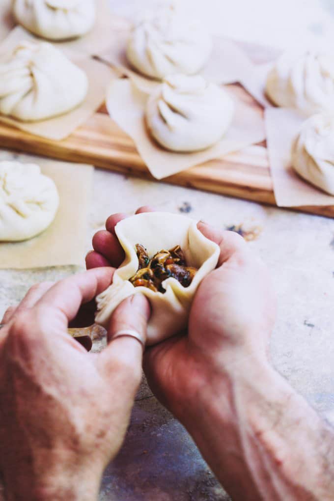 A pair of hands wrapping mushrooms in a vegan bao