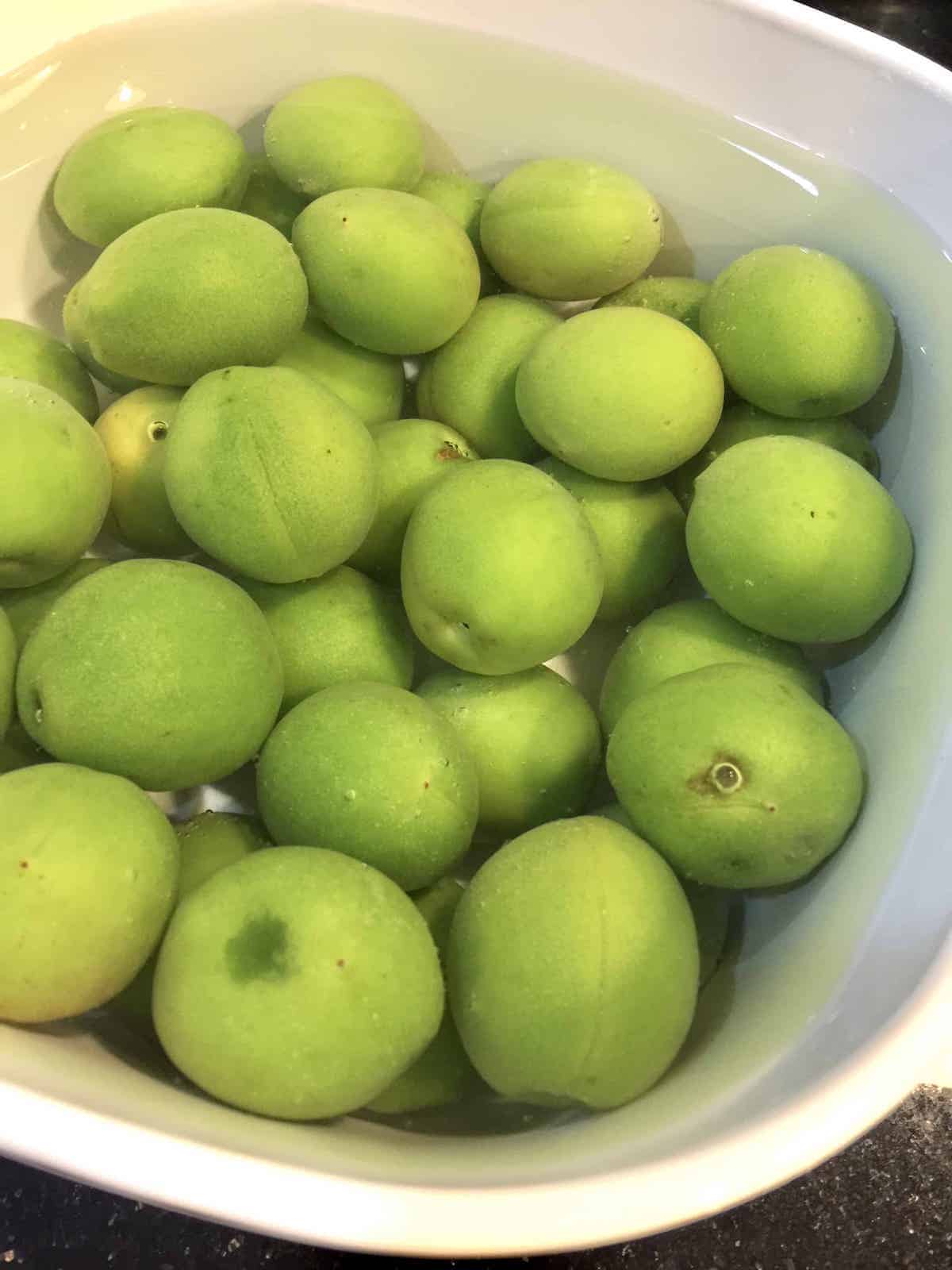 Green maesil soaking in baking soda to remove pesticides