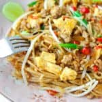 A fork dipped into a plate of Pad Mee Korat, a Northeastern Thai spicy stir fried noodle