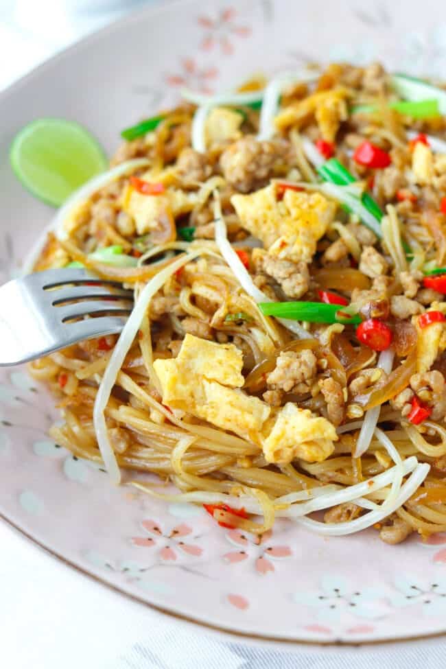 A fork dipped into a plate of Pad Mee Korat, a Northeastern Thai spicy stir fried noodle