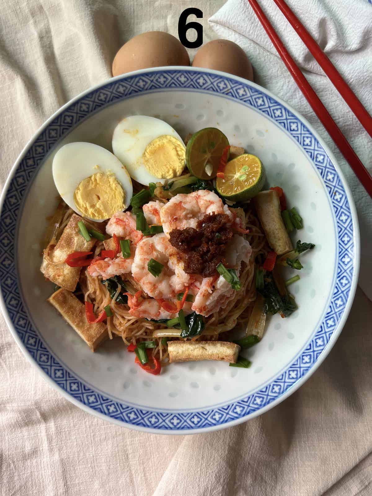A bowl of noodles with egg, prawns, chives and tofu.