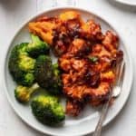 A plate of chicken in red sauce and broccoli