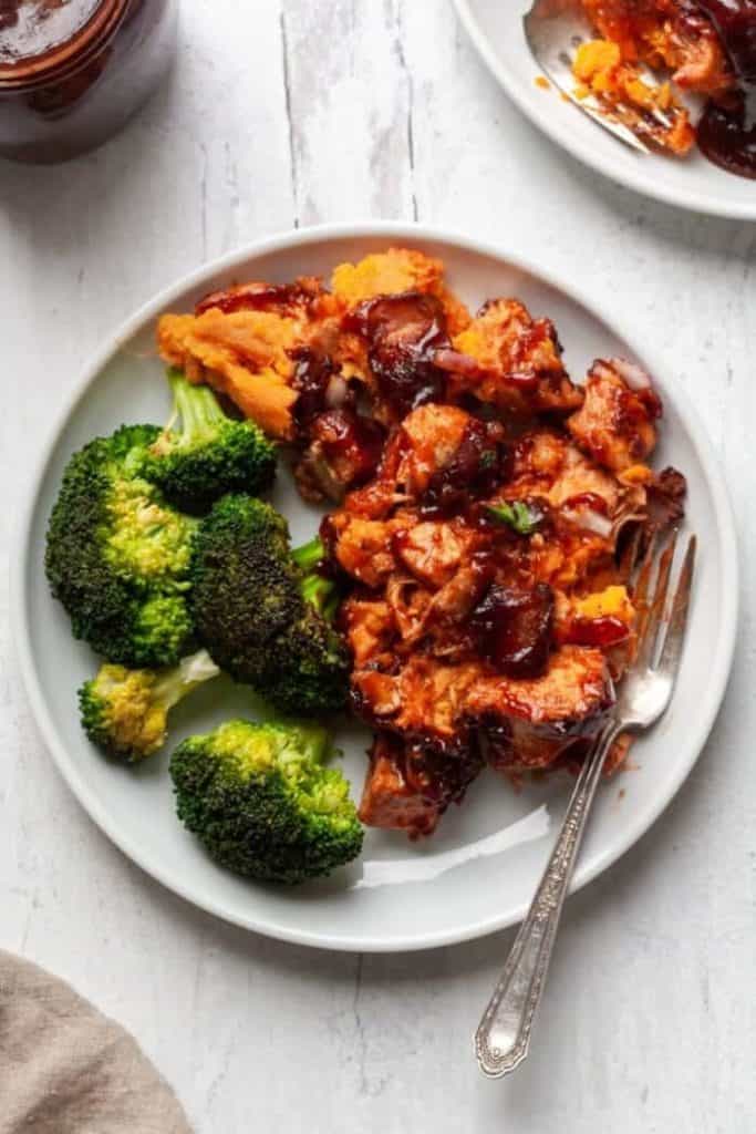 A plate of chicken in red sauce and broccoli