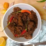 Beef rendang and chillies in a white bowl.