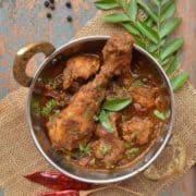 Chicken Chettinad curry with curry leaves in a silver pot.