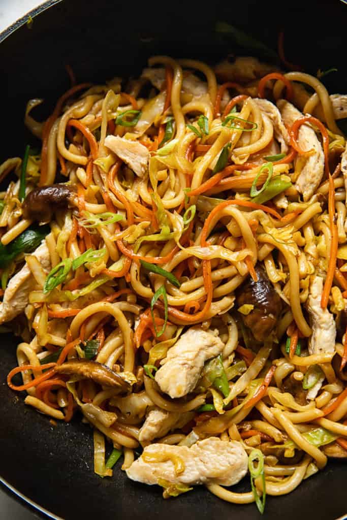 a close-up of a plate of chicken yaki udon noodles