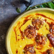 Overhead shot of a bowl of yellow creamy Kadhi with curry leaves.