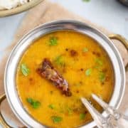 Orange lentil dal in a silver bowl.