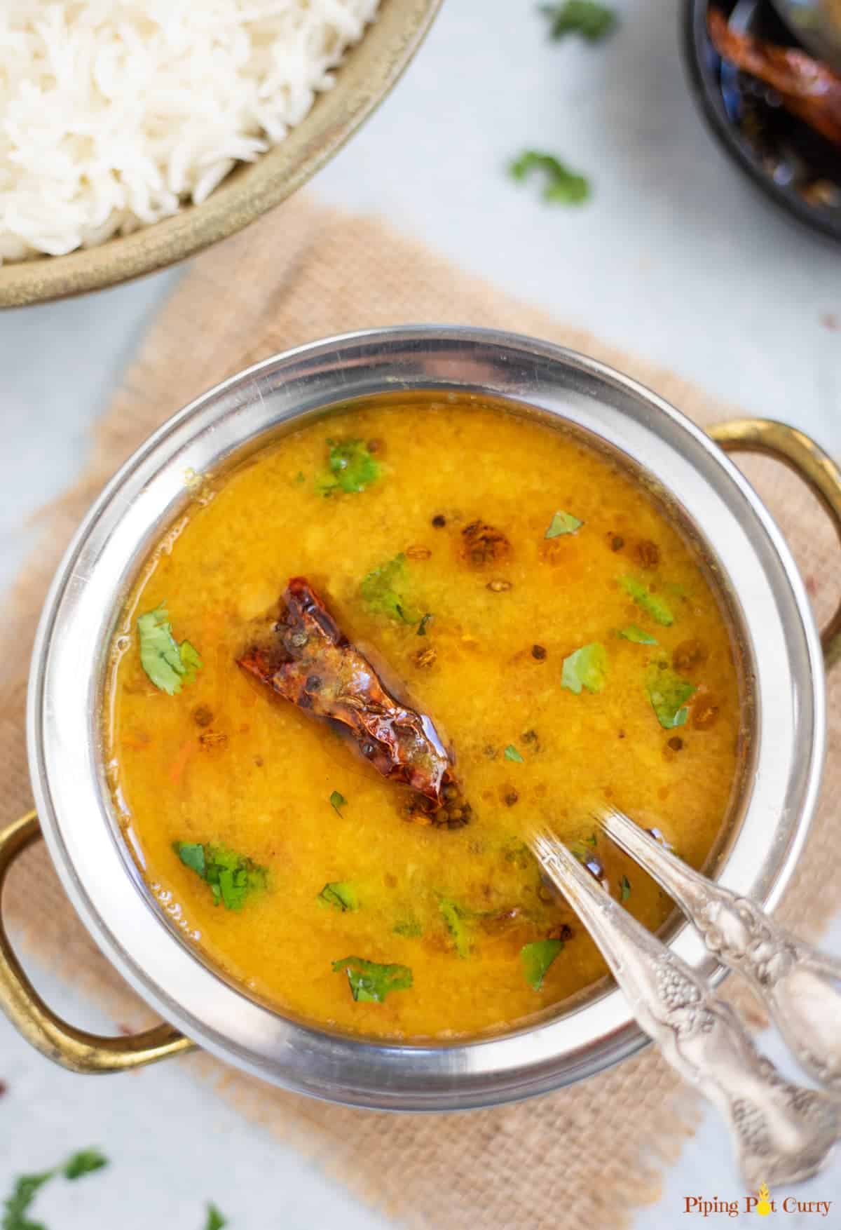 Orange lentil dal in a silver bowl.