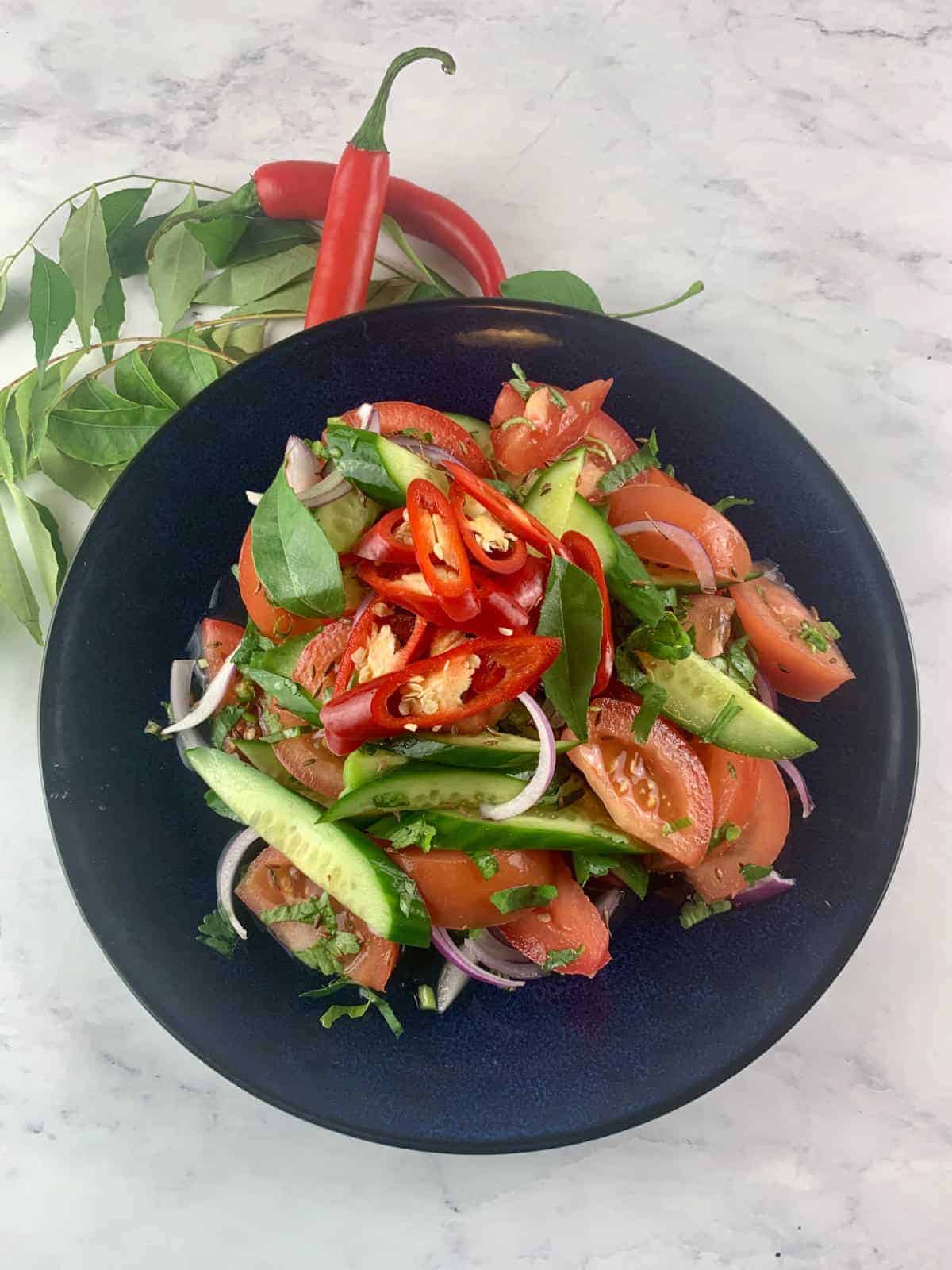 Indian cucumber salad in a dark blue bowl.