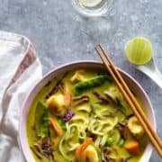 A bowl of noodles and lemongrass soup in a white bowl.