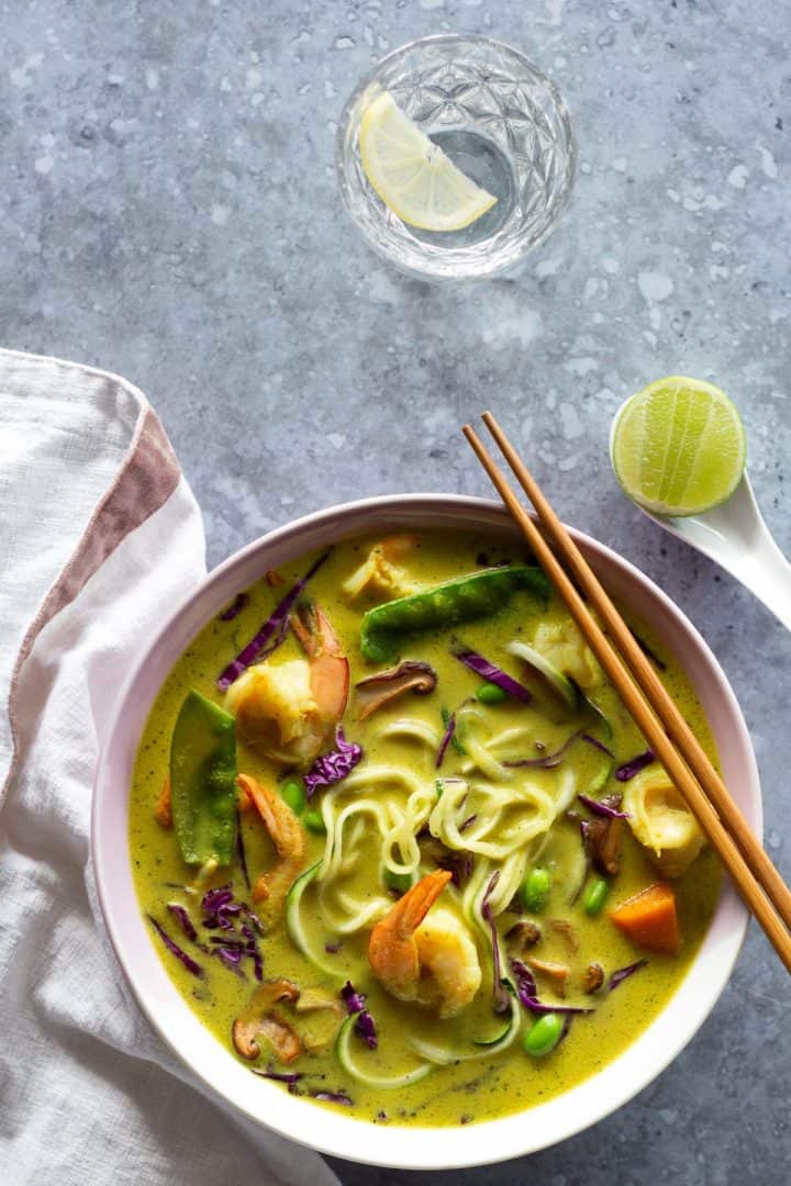 A bowl of noodles and lemongrass soup in a white bowl.