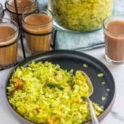 Yellow poha on a black plate.