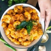 A close-up of shrimp masala garnished with curry leaves.