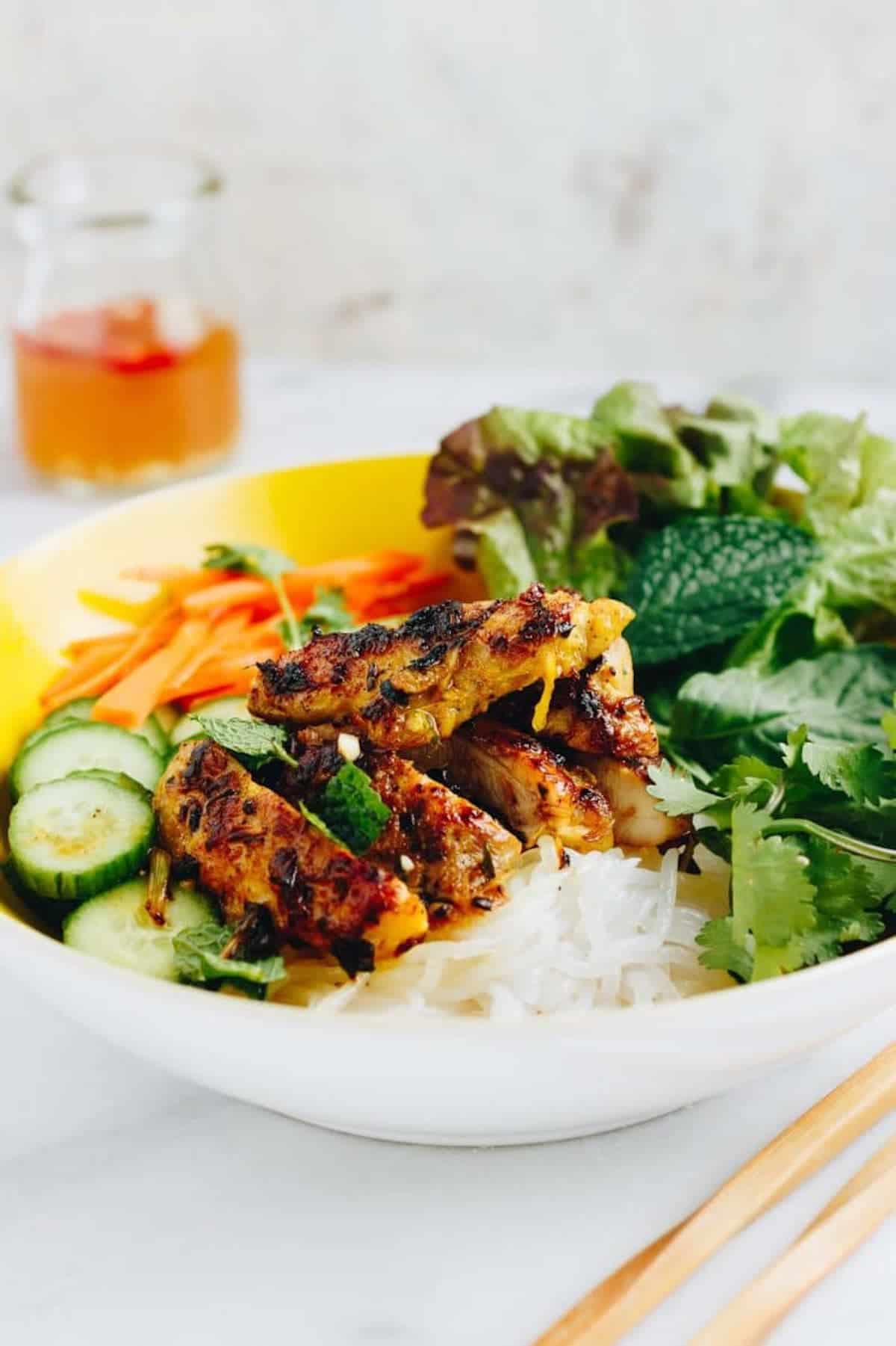 Grilled chicken on noodles in a white plate.