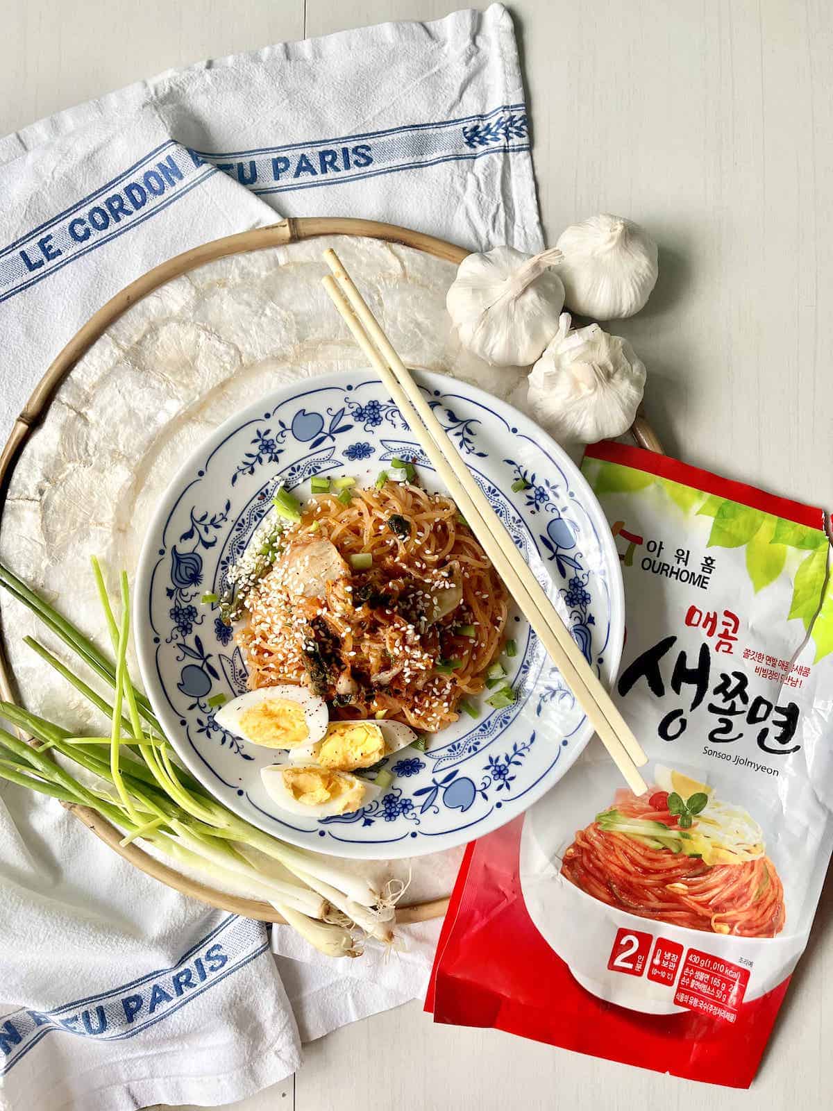 A plate of red cold noodles on top of an ourhome packet.