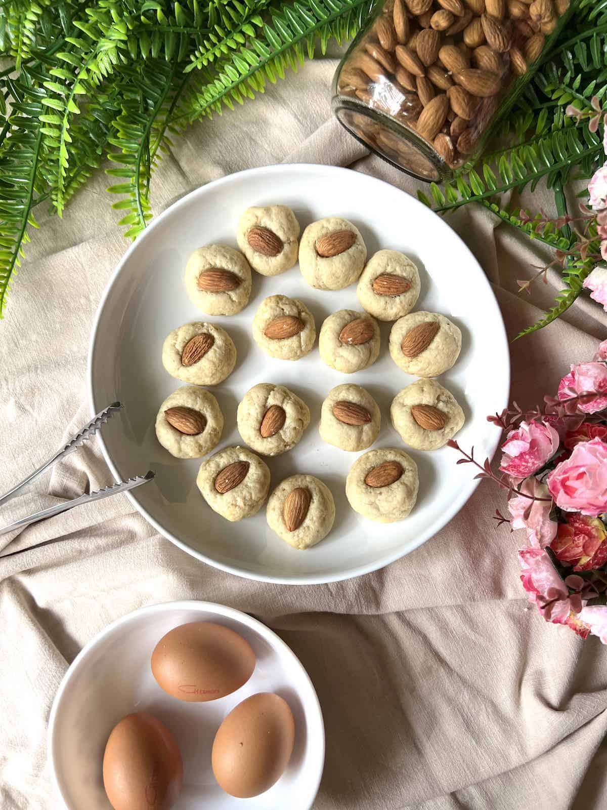 Many round almond cookies on a white plate.