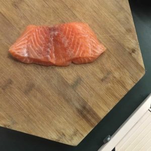 A piece of raw salmon on a wooden cutting board