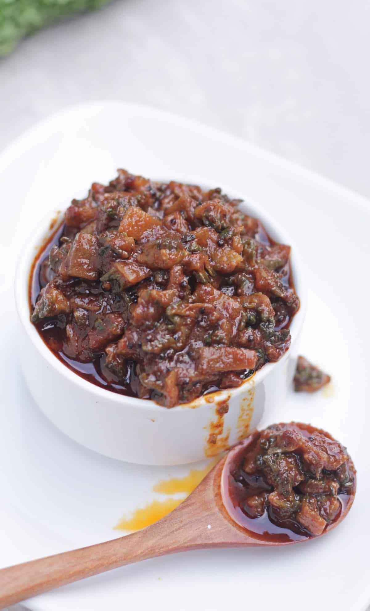 Bittergourd and tamarind pickle in a white bowl.