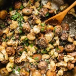 A pan of garlic mushrooms with cauliflower sprinkled on top