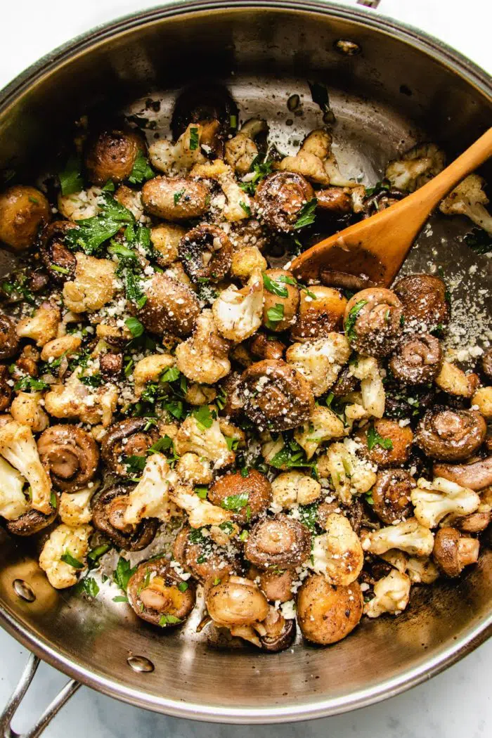 A pan of garlic mushrooms with cauliflower sprinkled on top