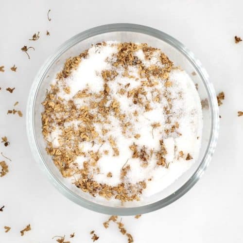 An overhead view of dried osmanthus flower tea with sugar in a glass bowl