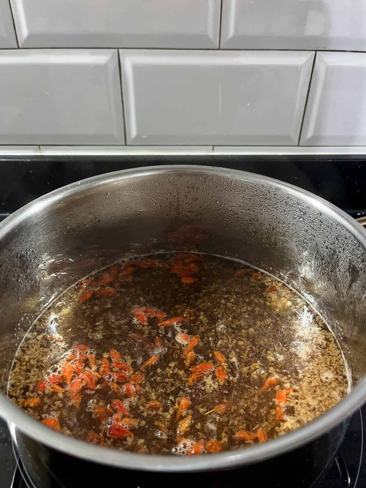 Dried goji berries added to a pot of osmanthus jelly.