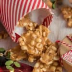 Chunks or peanut brittle spilling out of a red and white container