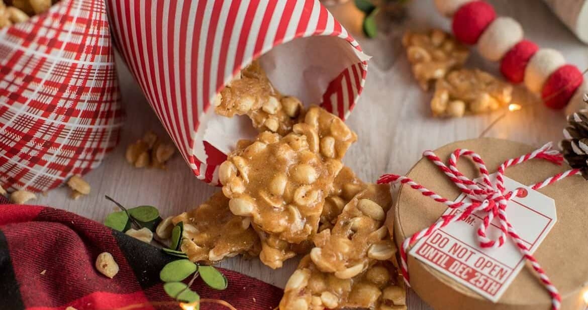 Chunks or peanut brittle spilling out of a red and white container