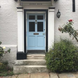A blue door framed by a black border in a white brick building
