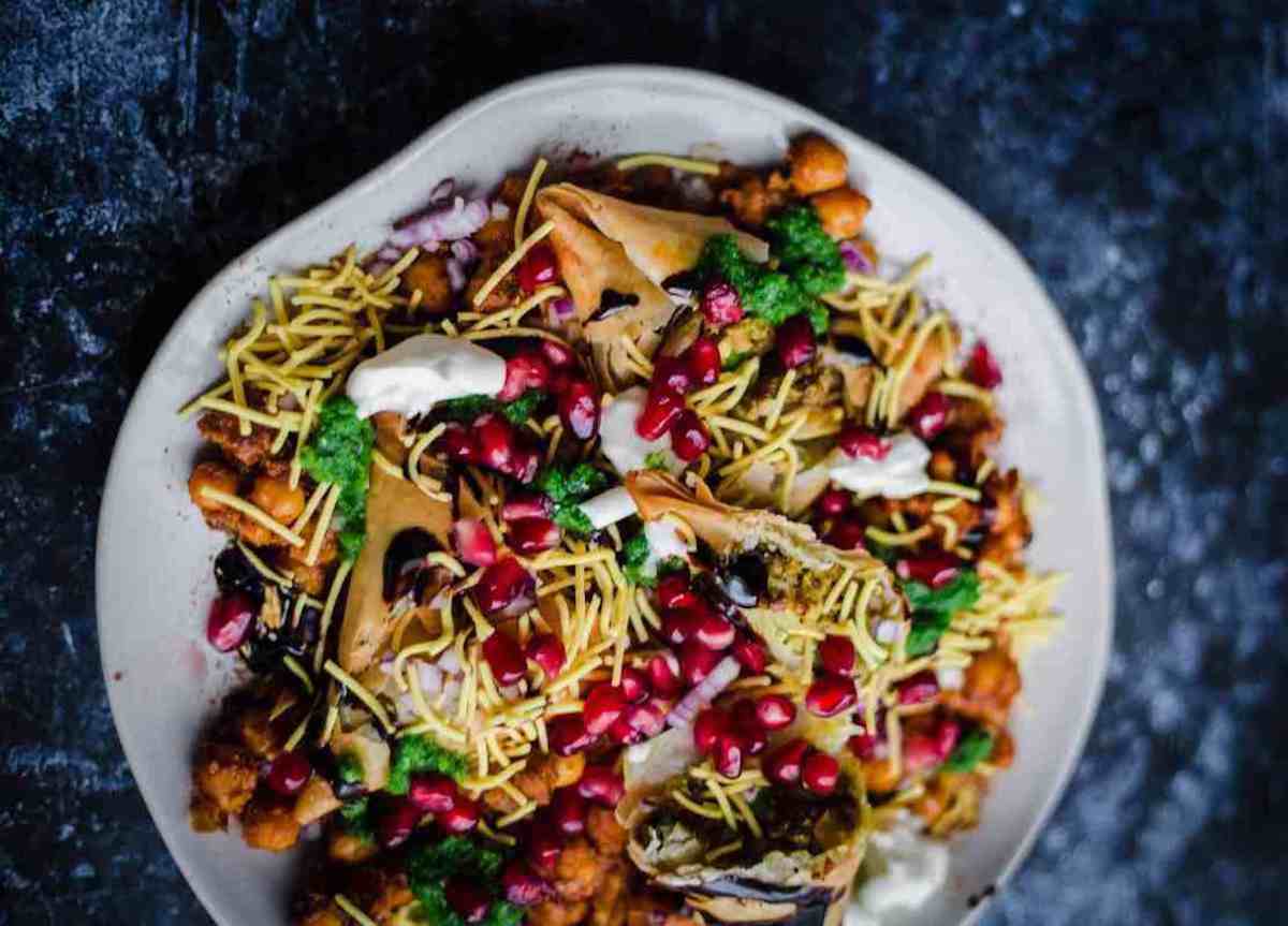 A colorful plate of samso chaat topped with tamarind dressing.