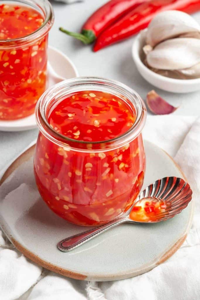 A glass jar full of a bright red sweet chilli sauce