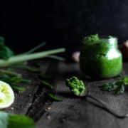 A spoonful of bright green curry paste next to lime and green chilies.