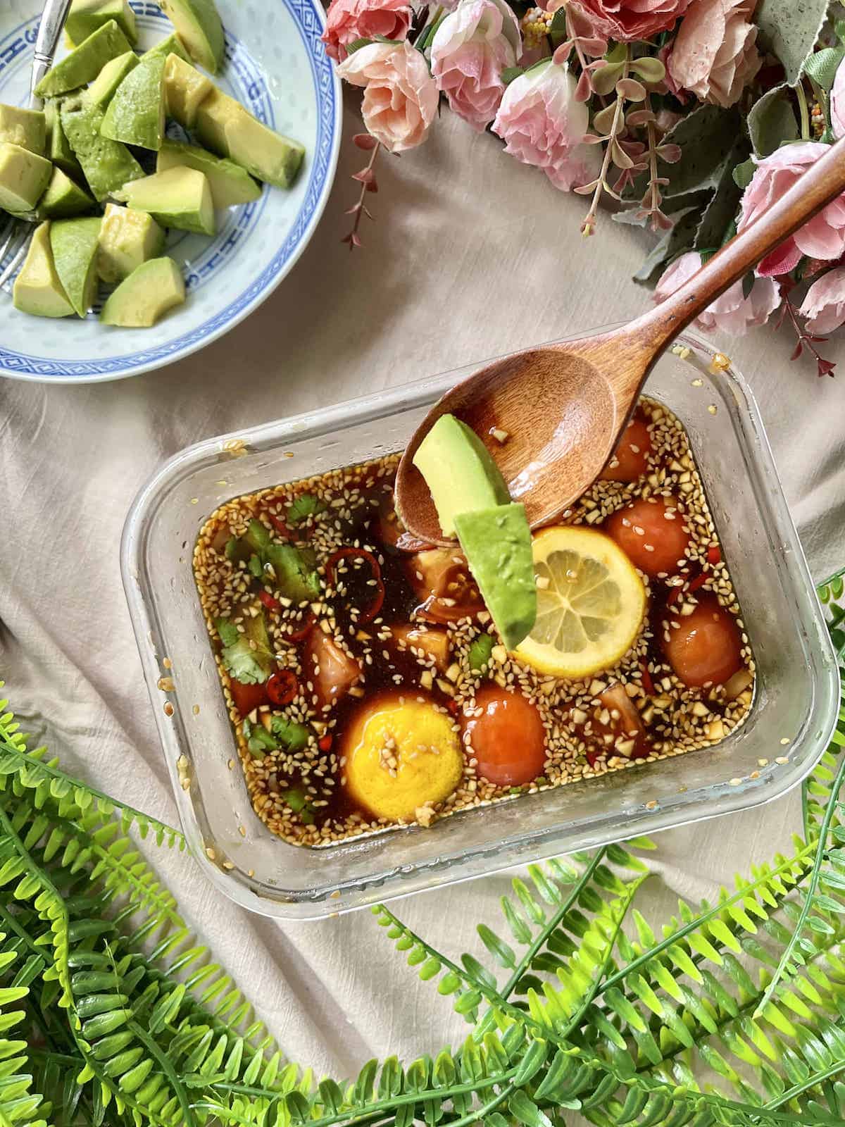 Using a wooden spoon to scoop avocado chunks into soy sauce brine.