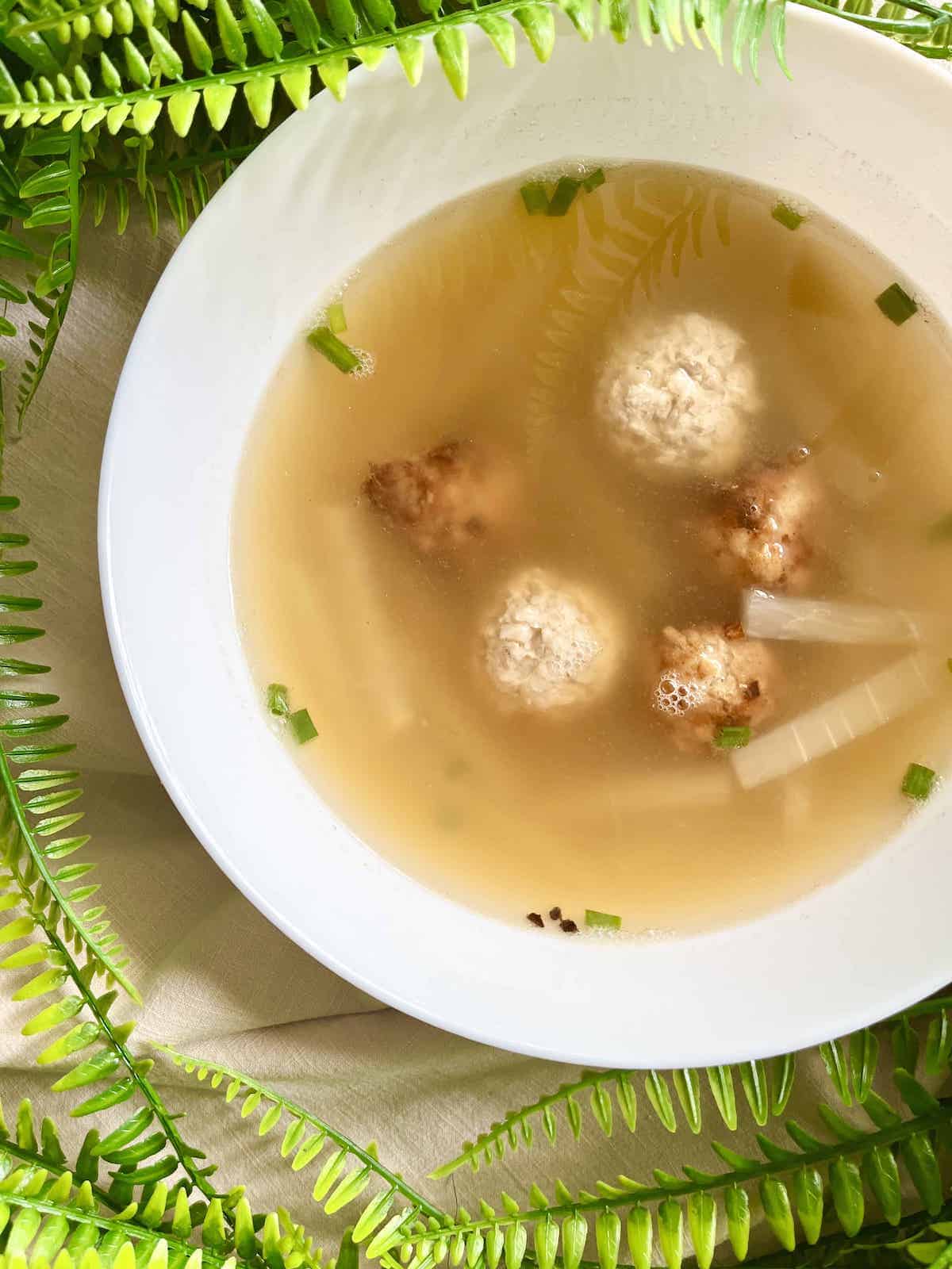 2 types of Chinese meatballs in a bowl of soup.