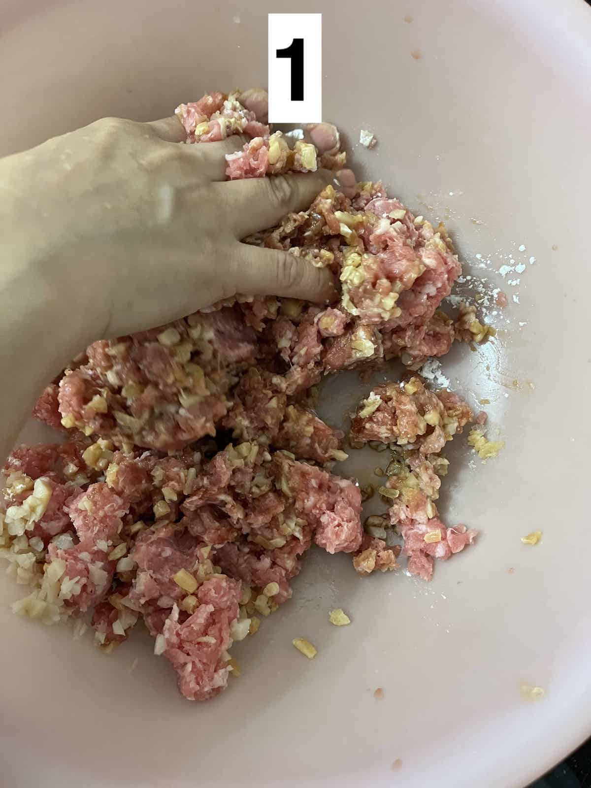 Mixing ground pork and other ingredients by hand.