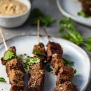 Indonesian beef satay on a white plate.