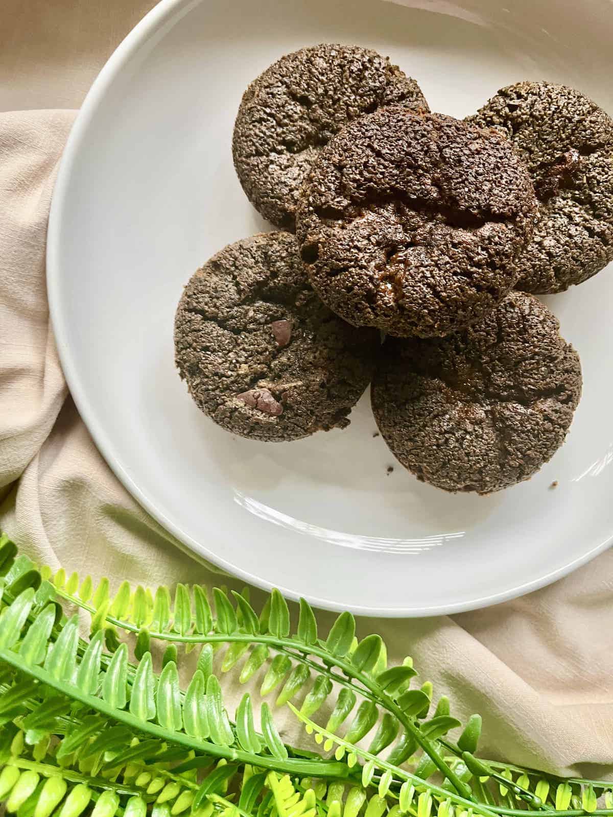 5 black sesame mochi muffins on a white plate.