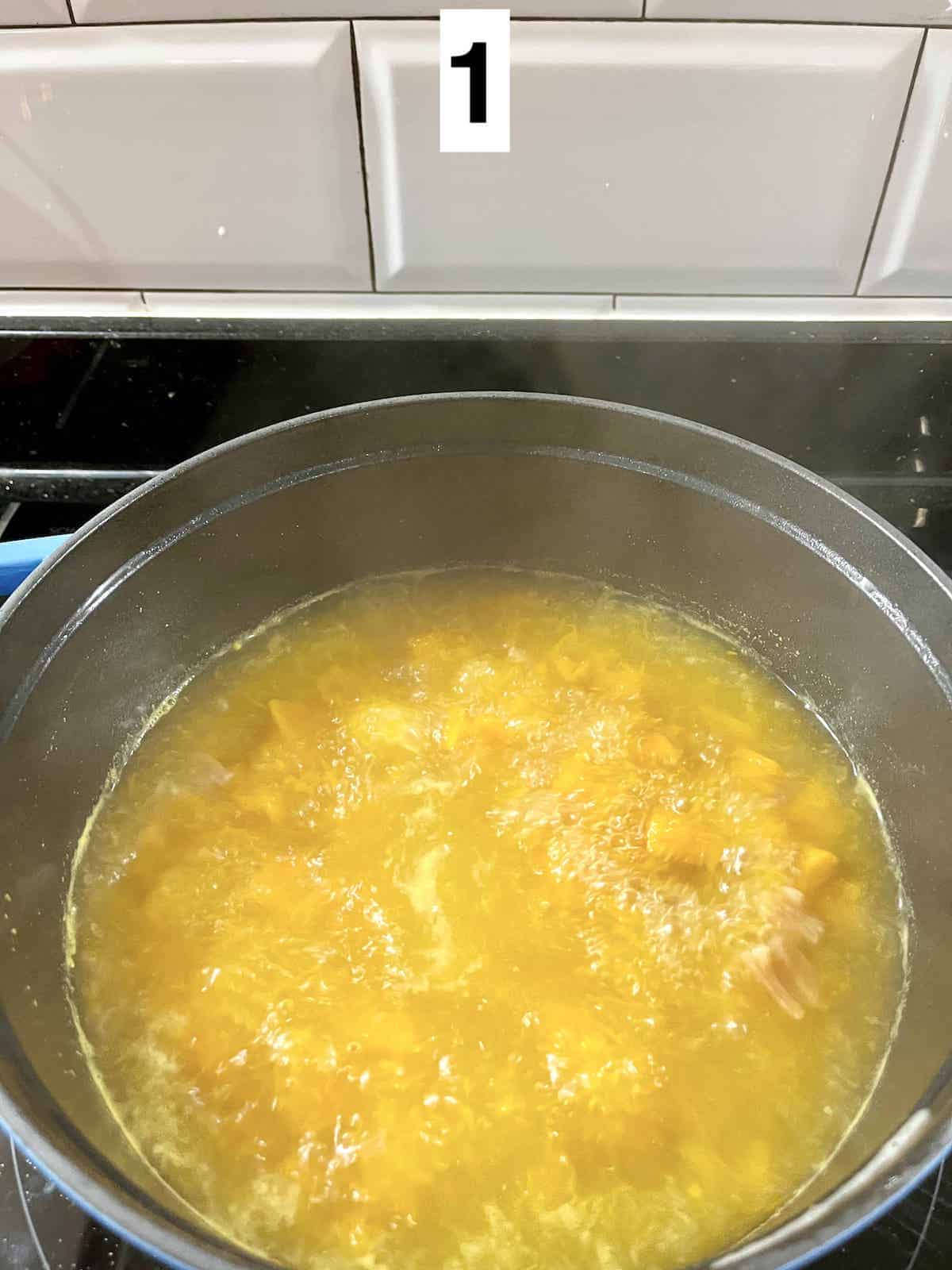 Boiling cubes of pumpkin and conpoy in chicken broth.